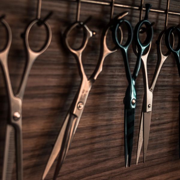 Multiple pairs of scissors hanging on a wooden wall rack.