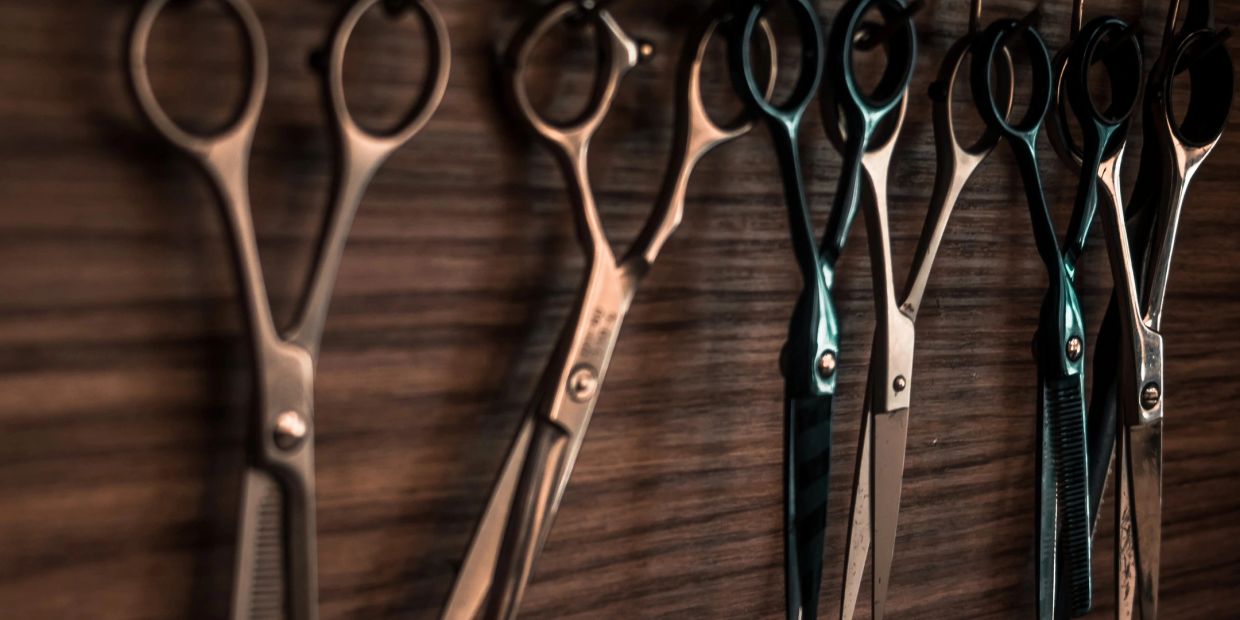 Row of hair cutting scissors on a wooden surface.