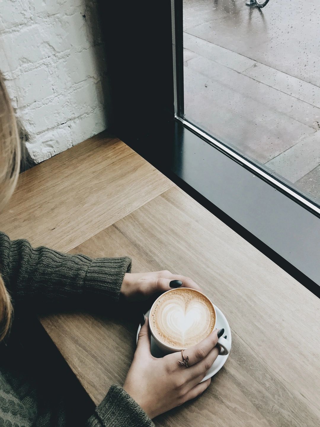 A woman sitting on a coffee bar drinking a late.