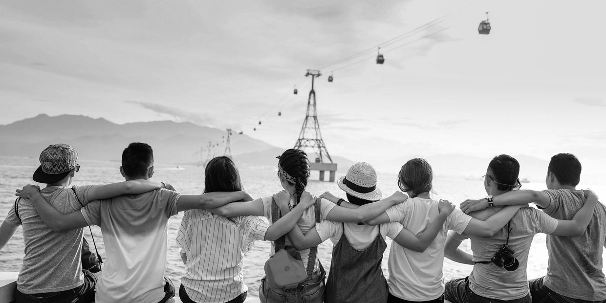 A group of people sitting on the side of a body of water.