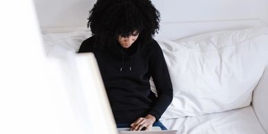 Lady sitting on modern white couch working on her laptop to get ready for college