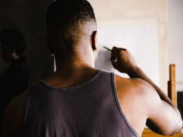Man sketching on a canvas in a dimly lit room.