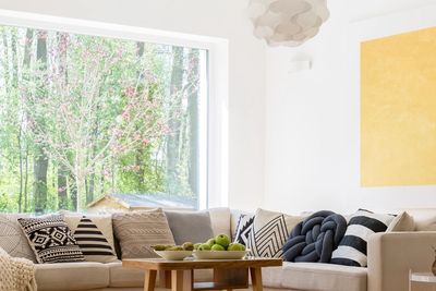 Cozy living room with neutral tones and patterned cushions near a large window.