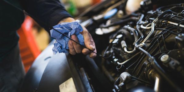 automotive technician checking oil level with engine dipstick