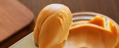 A knife spreading smooth peanut butter.