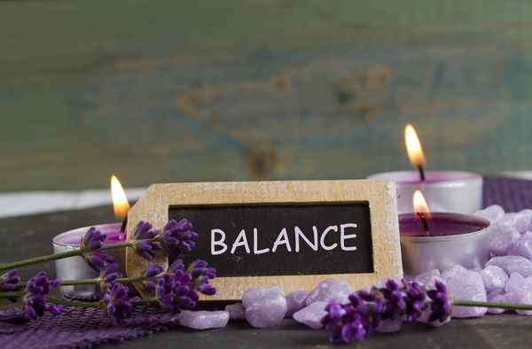 Lavender, candles, and a sign reading BALANCE create a calming scene.