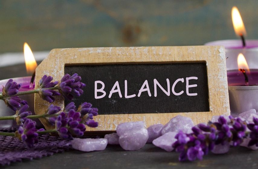 A rustic tag with the word BALANCE surrounded by candles and lavender.