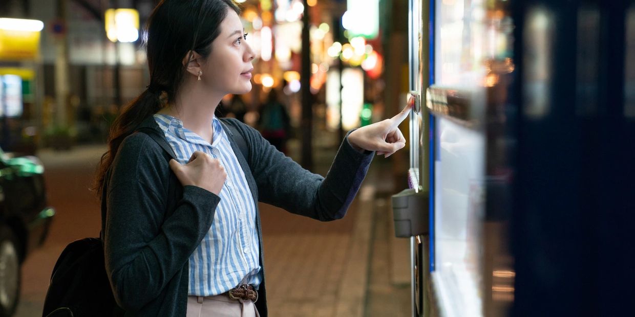 Woman, with black hair, selecting items on a vending machine.