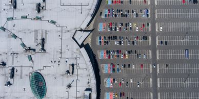 Aerial view of a building adjacent to a parking lot filled with cars.