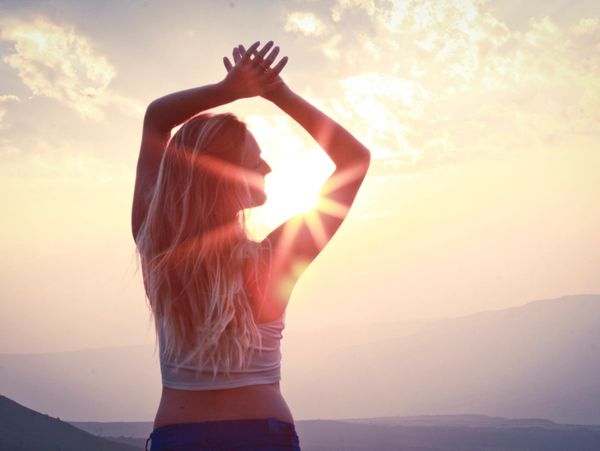 A happy client watching the sunset with her arms in the air 