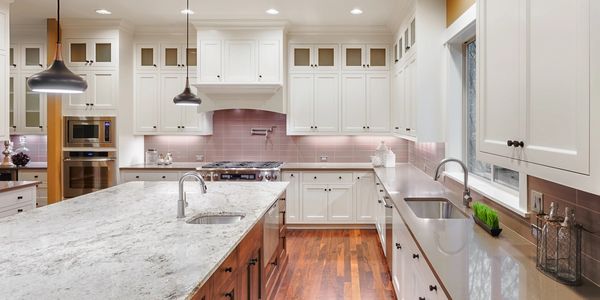 modern kitchen with white cabinets, tile backsplash large island with grey granite, brown countertop