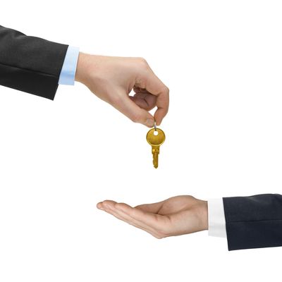 One hand handing over a golden key to another hand below it.