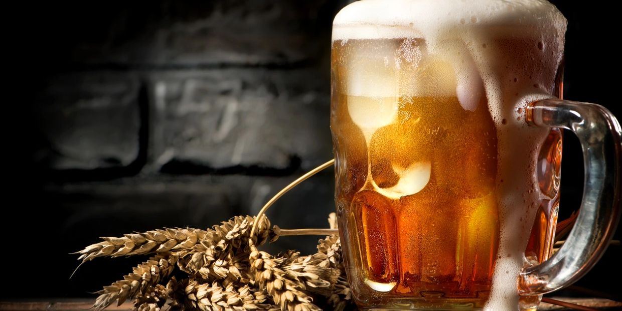 A frothy beer mug with wheat stalks.