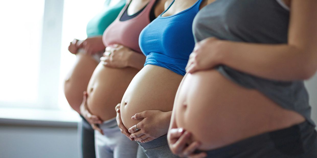 Four pregnant women showing their baby bump during a childbirth education class. Nashville, Doula