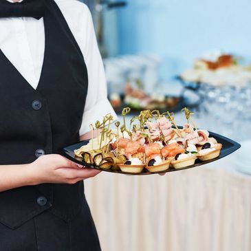 Waiter holding a tray of assorted appetizers at an event.