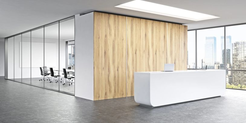 Modern office lobby with sleek white reception desk and glass-walled meeting room.