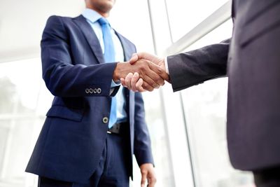 Two businessmen shaking hands in a bright office setting.