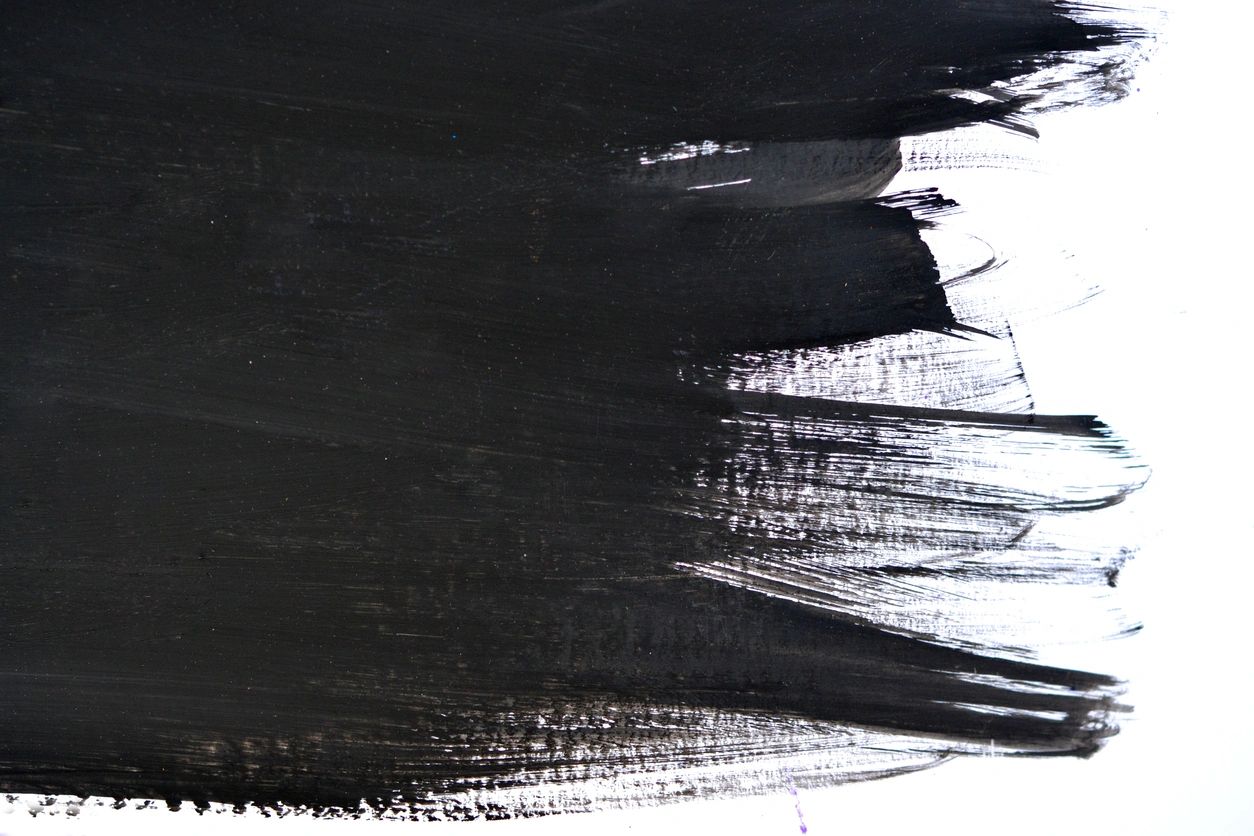 Black paint strokes on a white surface with textured brush marks.