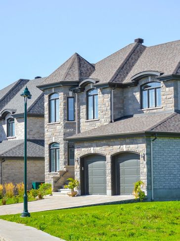 Modern stone houses with gray roofs under a clear blue sky.