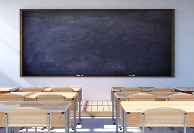 Empty classroom with wooden desks and a large blackboard.