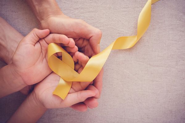 Hands holding a yellow ribbon symbolizing awareness and support.
