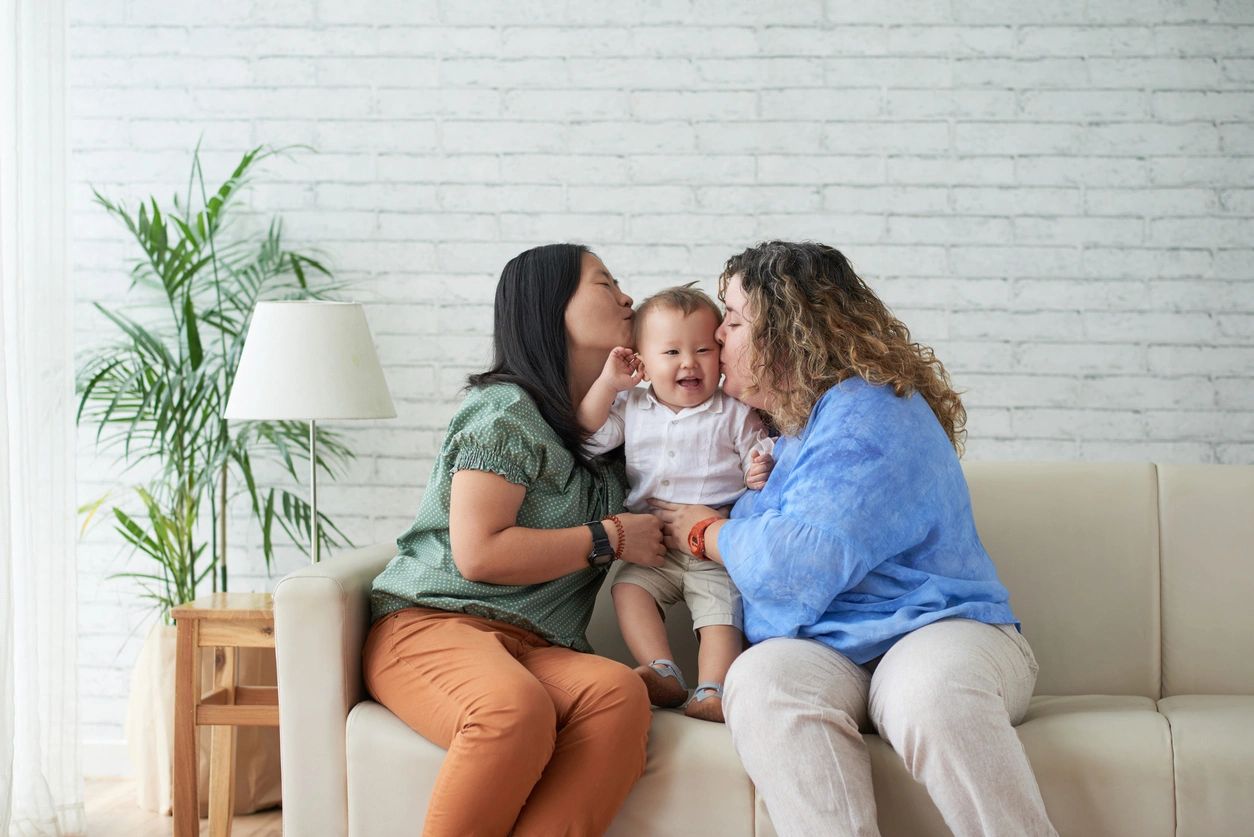 two women kissing a baby