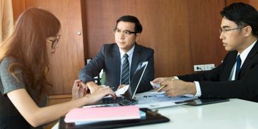 Three professionals engaged in a business meeting in an office.