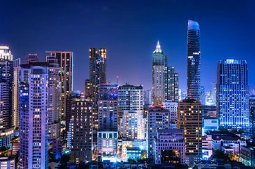 Nighttime city skyline with illuminated skyscrapers and buildings.