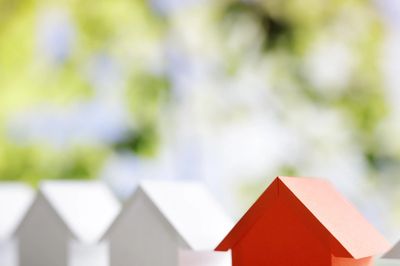 A small red house model stands out among white house models.