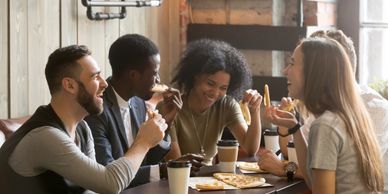 group of young friends at a restaurant (multiracial) laughing and eating