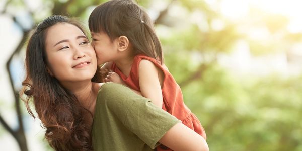 A child whispers to her mother outside.