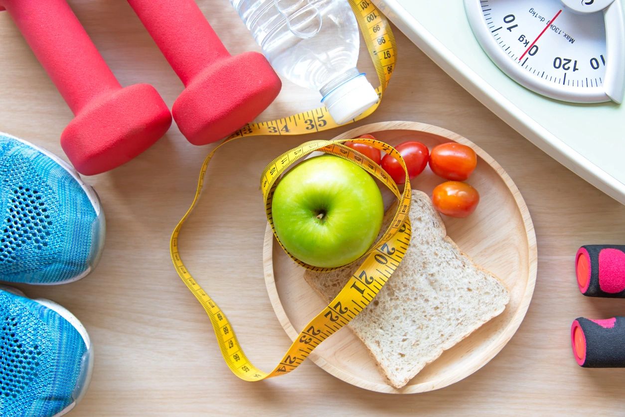 Dumbbells, sneakers, a body-weight scale, a bottled water, measuring tape and a light breakfast show a discipline of acquiring personal growth.