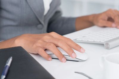 Person using a computer mouse with keyboard nearby.