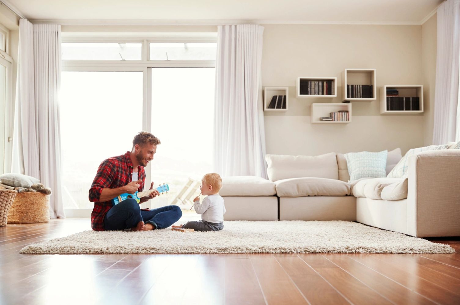 Father playing ukulele for baby in cozy living room.