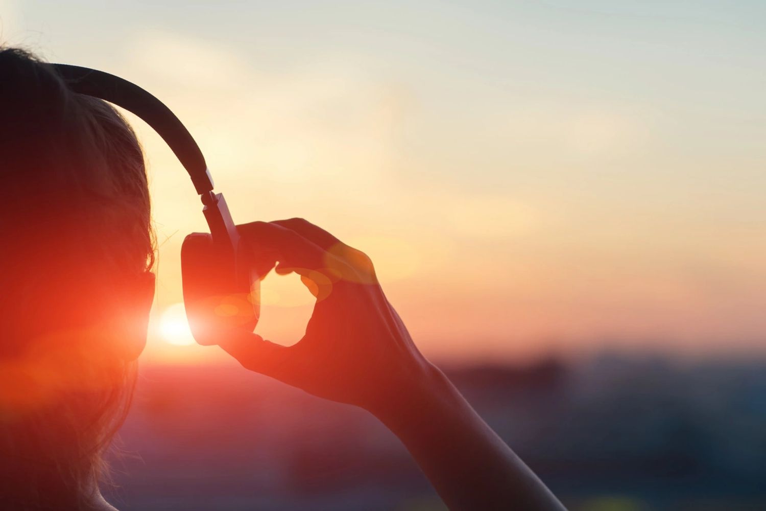 Person watching sunset with headphones.