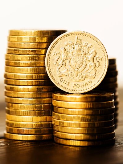 Stacks of one-pound coins on a wooden surface.