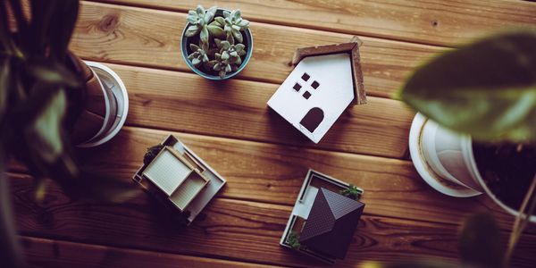 Toy houses and potted plants on top of a wooden table.