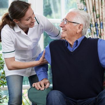 Nurse warmly assisting an elderly man at home.