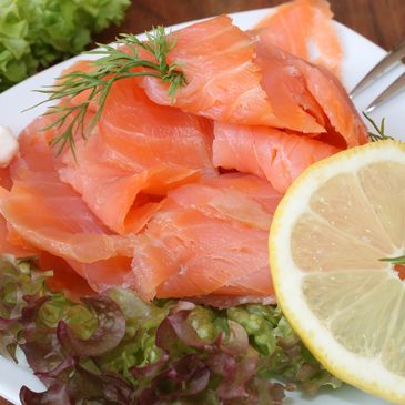 Plate of smoked salmon garnished with dill, lemon, and lettuce.
