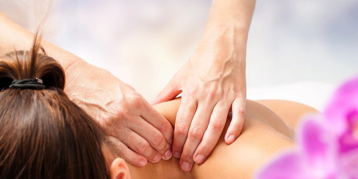 Person receiving a shoulder massage with hands applying pressure.