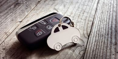Car key fob with a car-shaped keychain on a wooden surface.