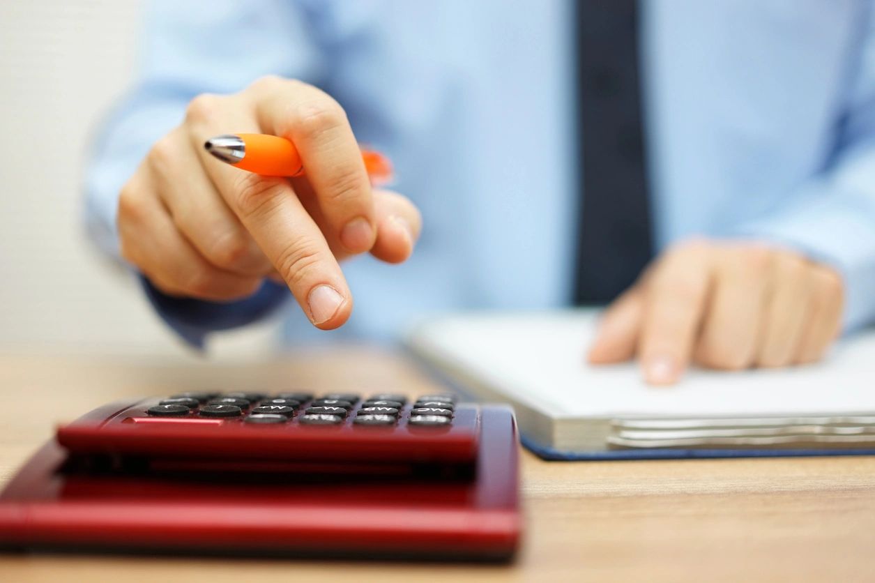 Person doing calculations with a pen, pad and calculator on a potential rental property where the FREE rental property calculator would help greatly.