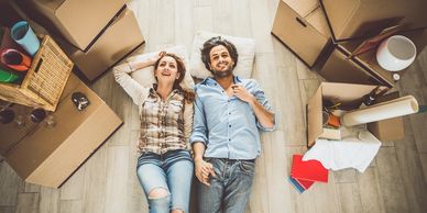 Buyers or sellers laying in the floor of their home with boxes surrounding them.