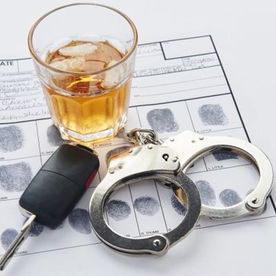 A glass of whiskey, car key, and handcuffs on a fingerprint card.