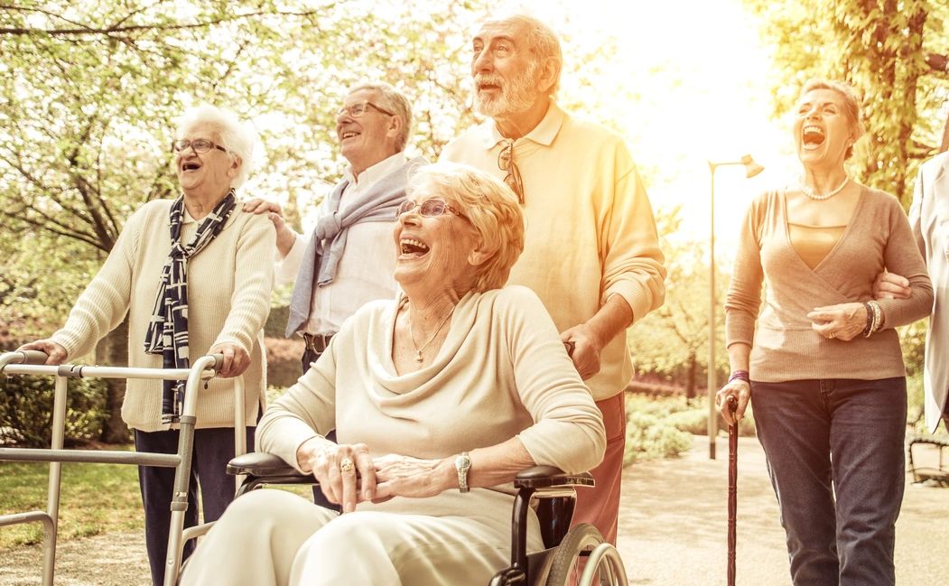 A joyful group of elderly friends enjoying a sunny walk outdoors.