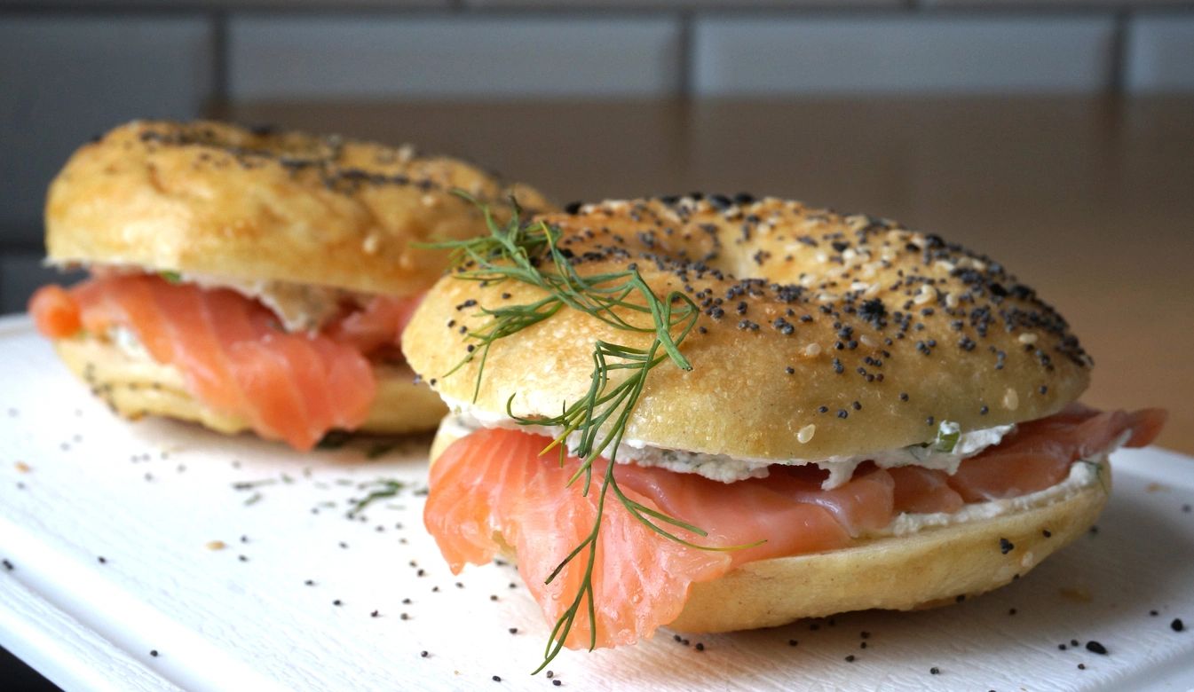 Two bagels with cream cheese and smoked salmon, garnished with dill.