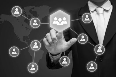 Businessman interacting with a virtual network of connected people icons.
