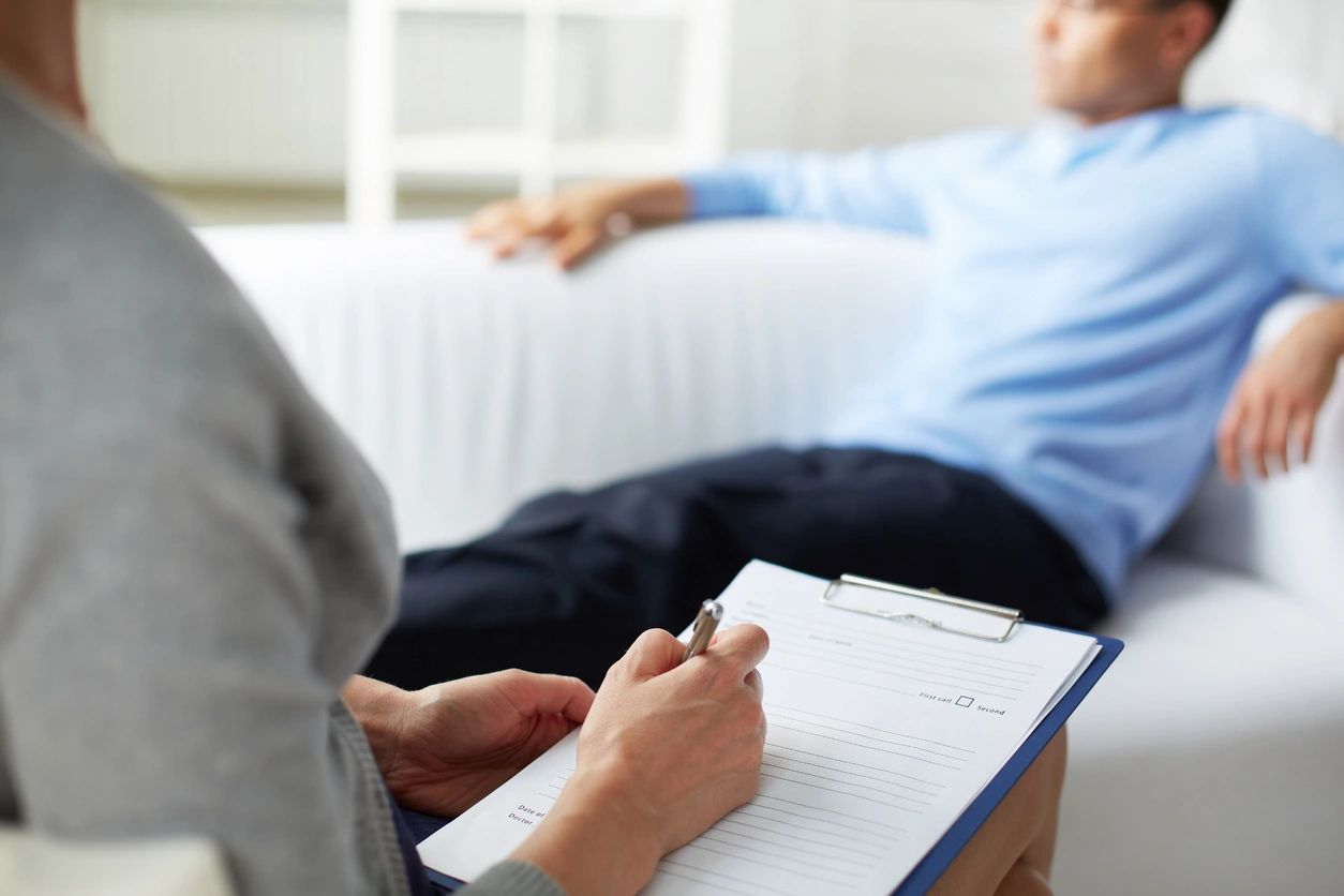 A Psychologist takes notes on a clipboard during a clients session for therapy or assessment 