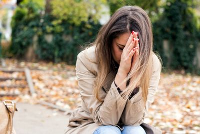 A girl sitting in a peaceful setting with her hands together in prayer.