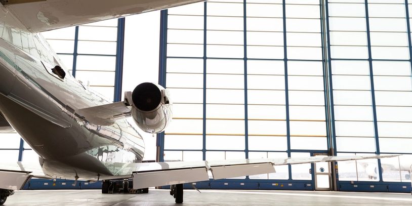 Private jet parked inside a spacious hangar with large windows.